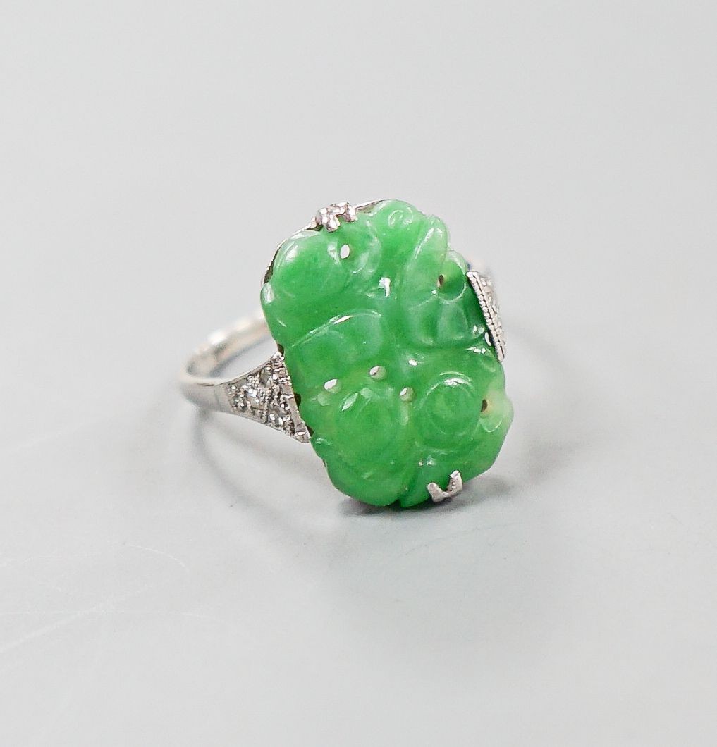 A 1920's 18ct, plat and carved jadeite oval dress ring, size O, gross weight 3.8 grams.